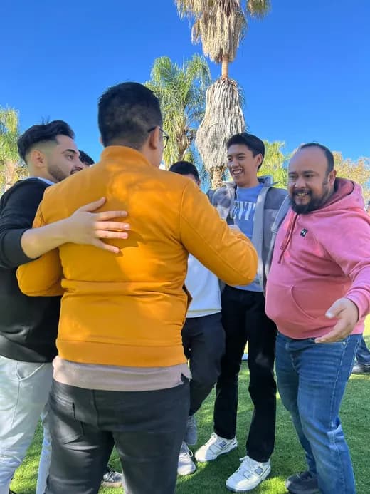 Compañeros se reúnen abrazados y sonríen durante una actividad de equipo.