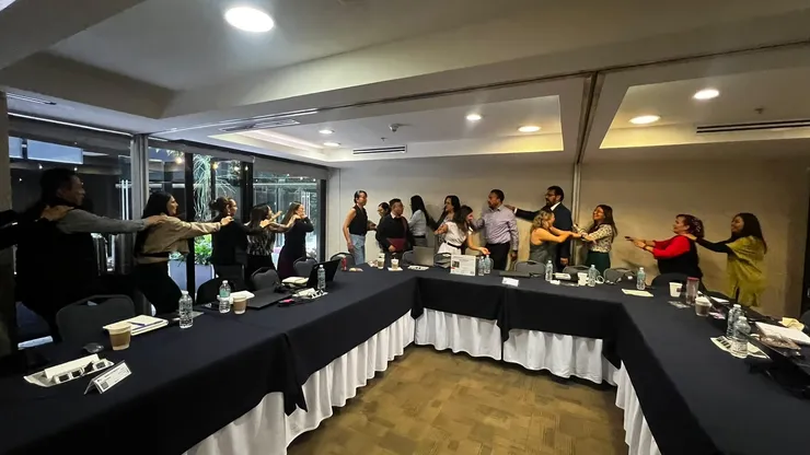 Un equipo participa de pie en una dinámica dentro de una sala.